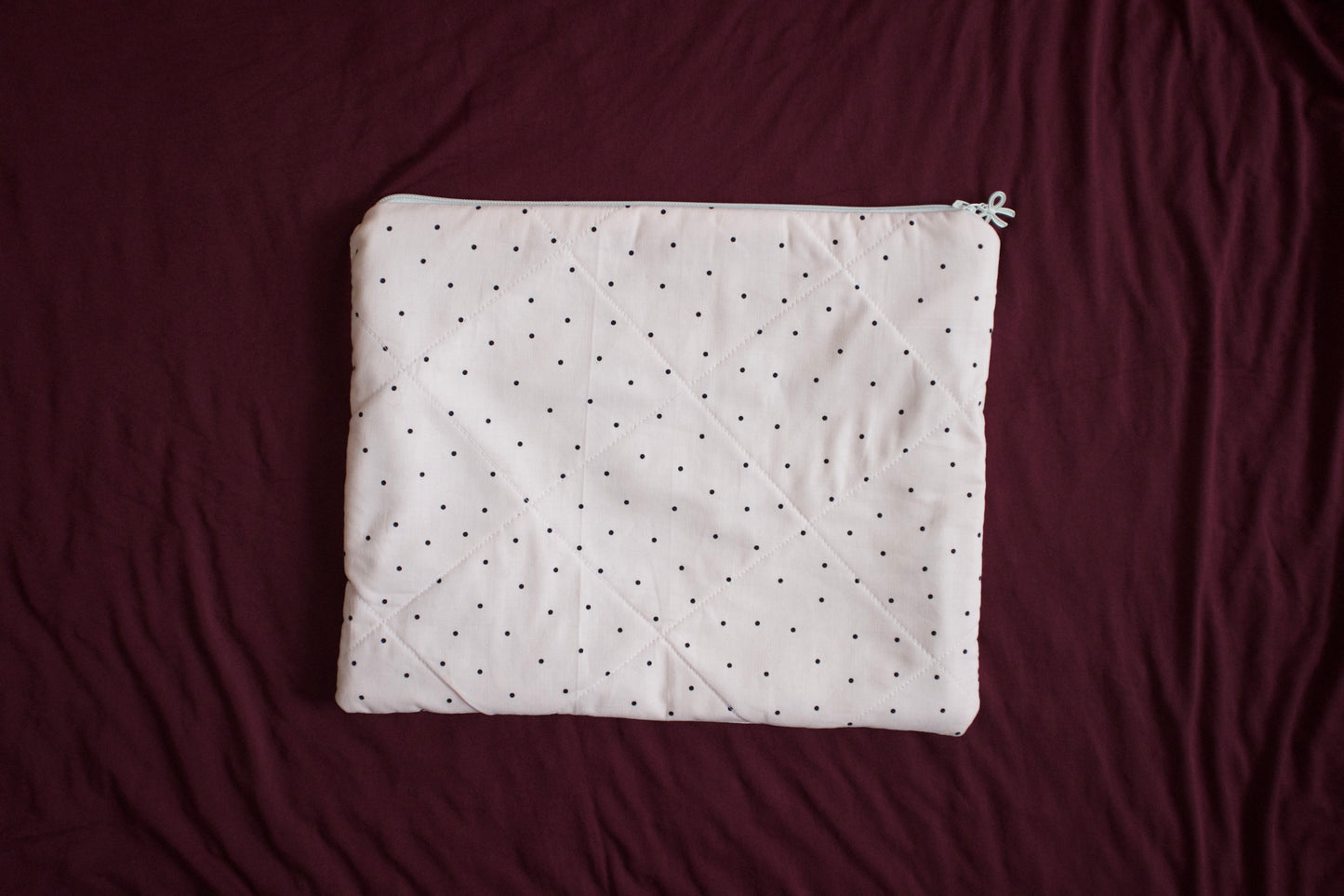 White quilt with black polka dots on a maroon background