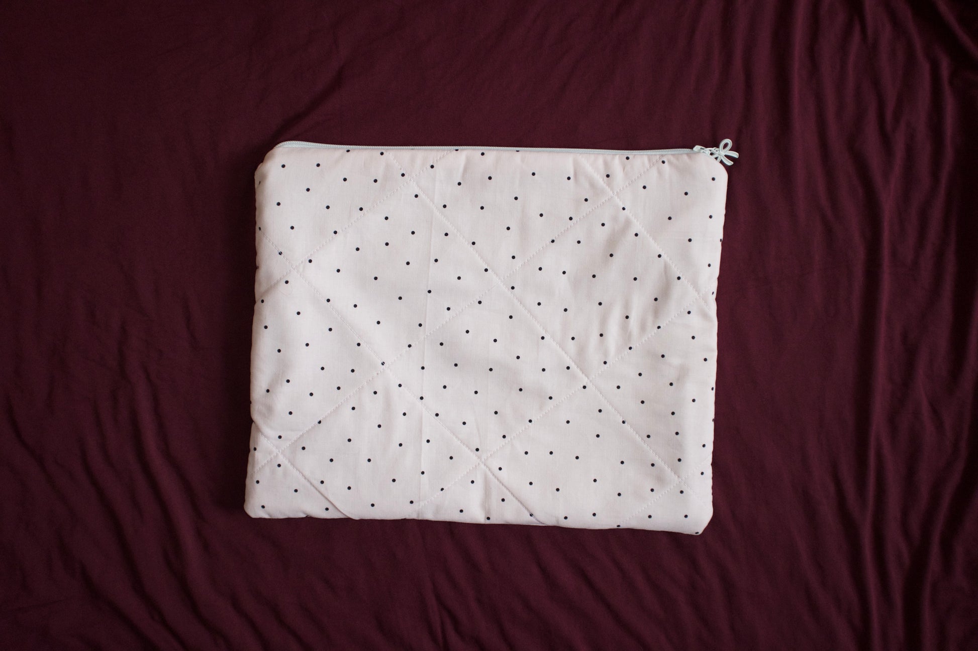 White quilt with black polka dots on a maroon background
