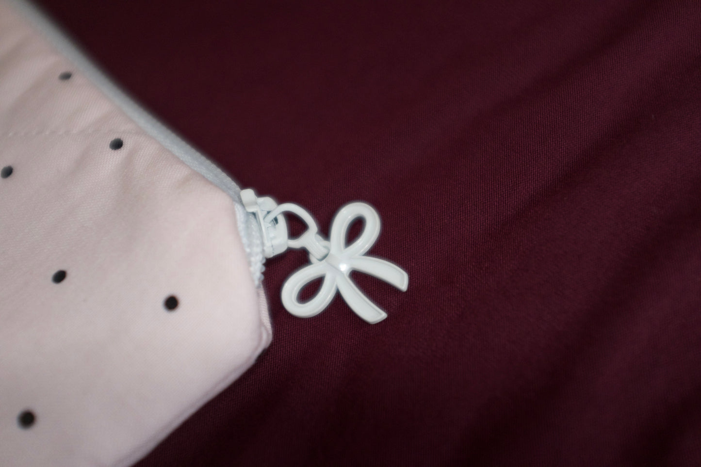 Close-up of a white flower-shaped charm on a maroon fabric background