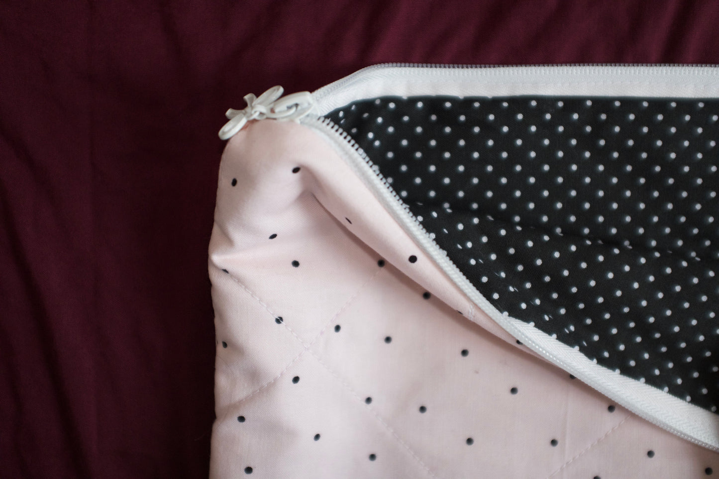 Close-up of a pink fabric with black polka dots and a zipper on a dark background